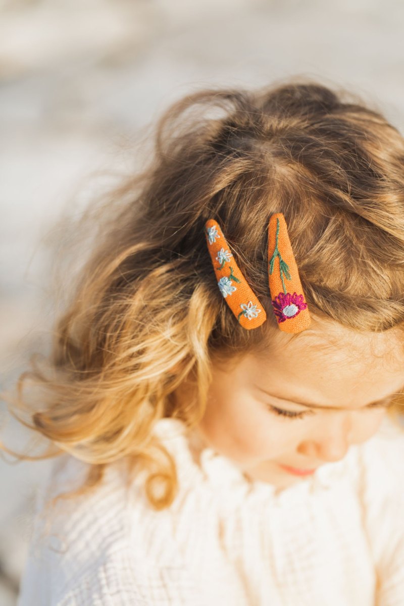 Curly-haired toddler girl wearing cute handmade flower hairpins