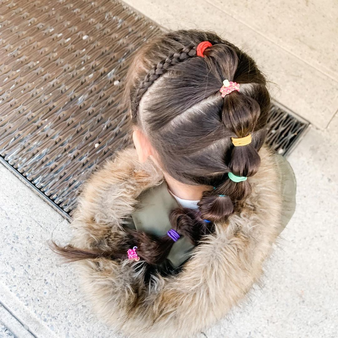 Toddler girl with double bubble braids tied with colorful elastics