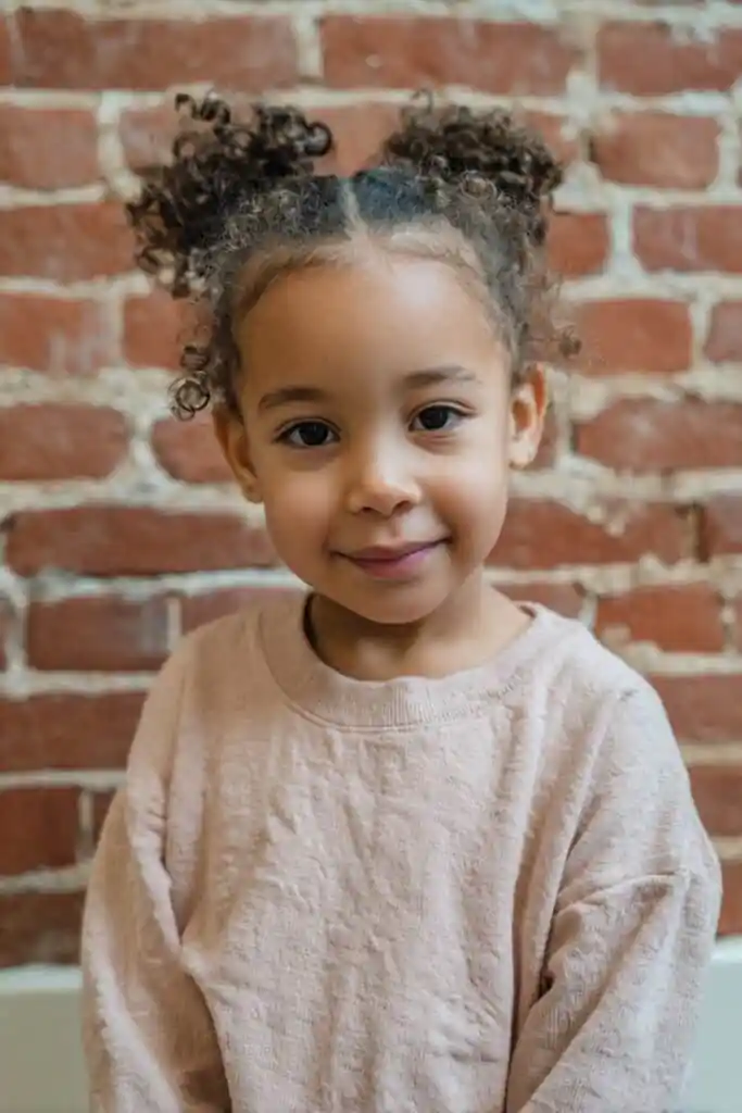Toddler girl with natural curls styled in a high pineapple puff