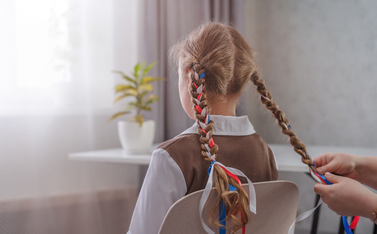 Mother braiding her little girl's pigtails with ribbons woven in