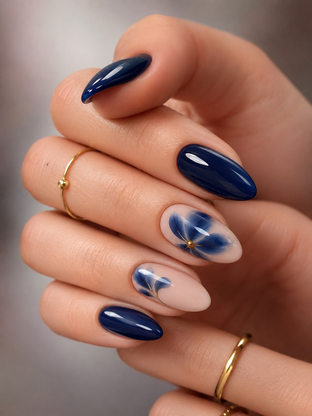 Navy blue glossy nails with a painted flower accent, an unexpected neutral for deep skin tones