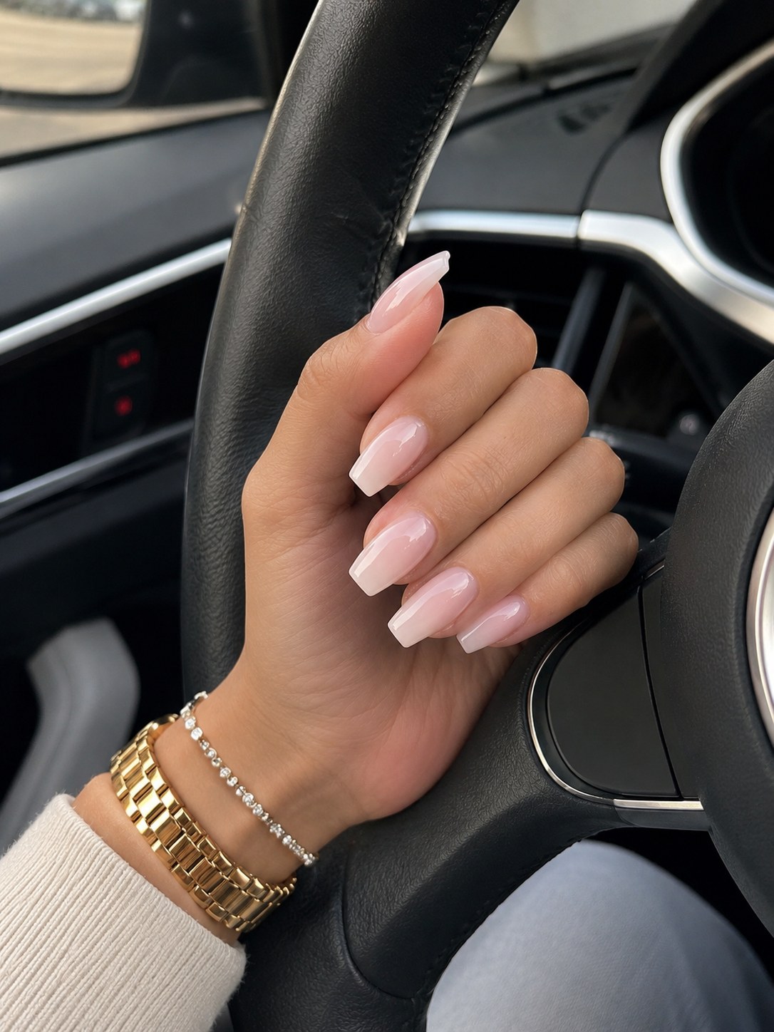 Glazed milk-bath nude nails in a car, a pink-toned nail colour that flatters deep skin tones