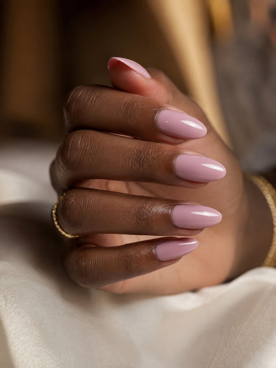 Glossy dusty mauve nail colour on an almond manicure suited to deep skin tones