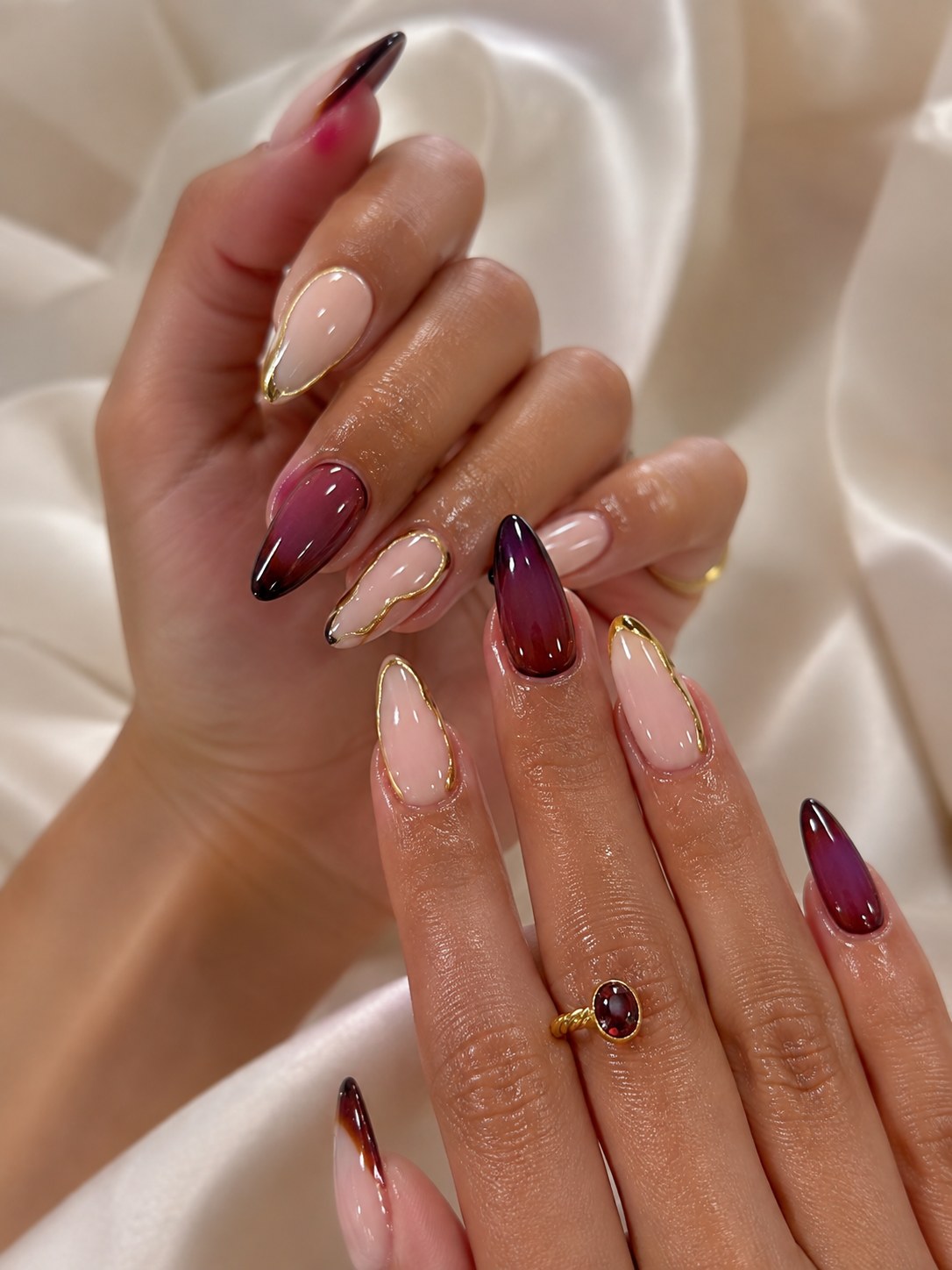 Wine marble nail art with gold liner accents, a party-season nail colour for deep skin tones