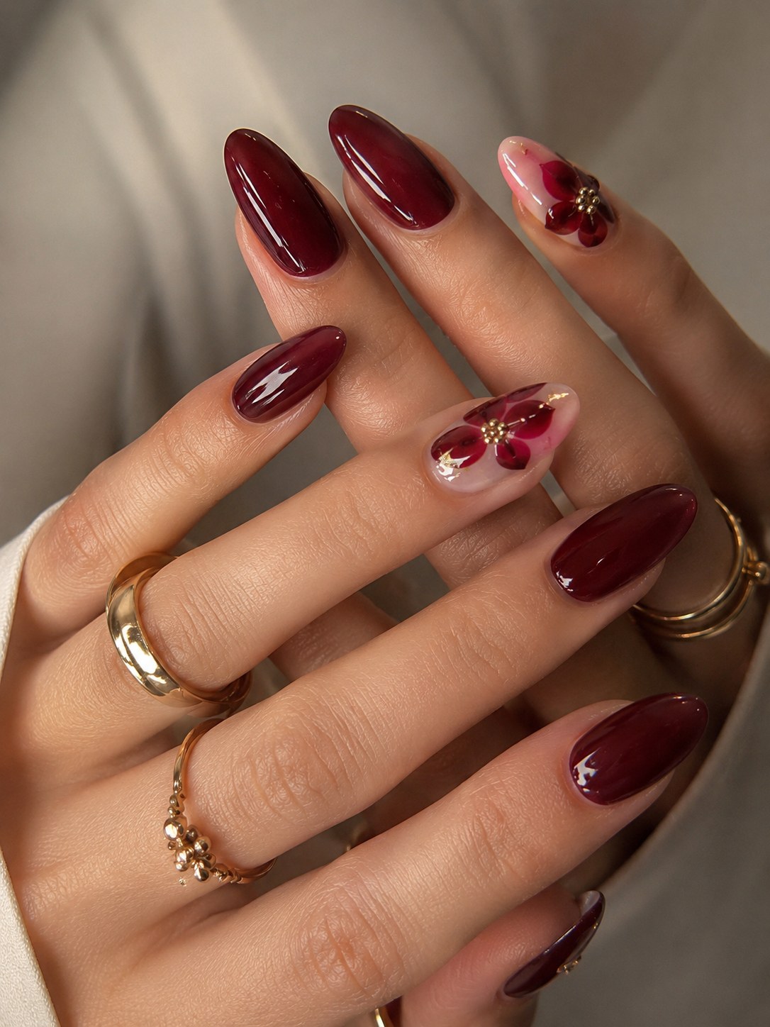Deep wine red nails with a hand-painted floral accent nail, a jewel tone for deep skin tones