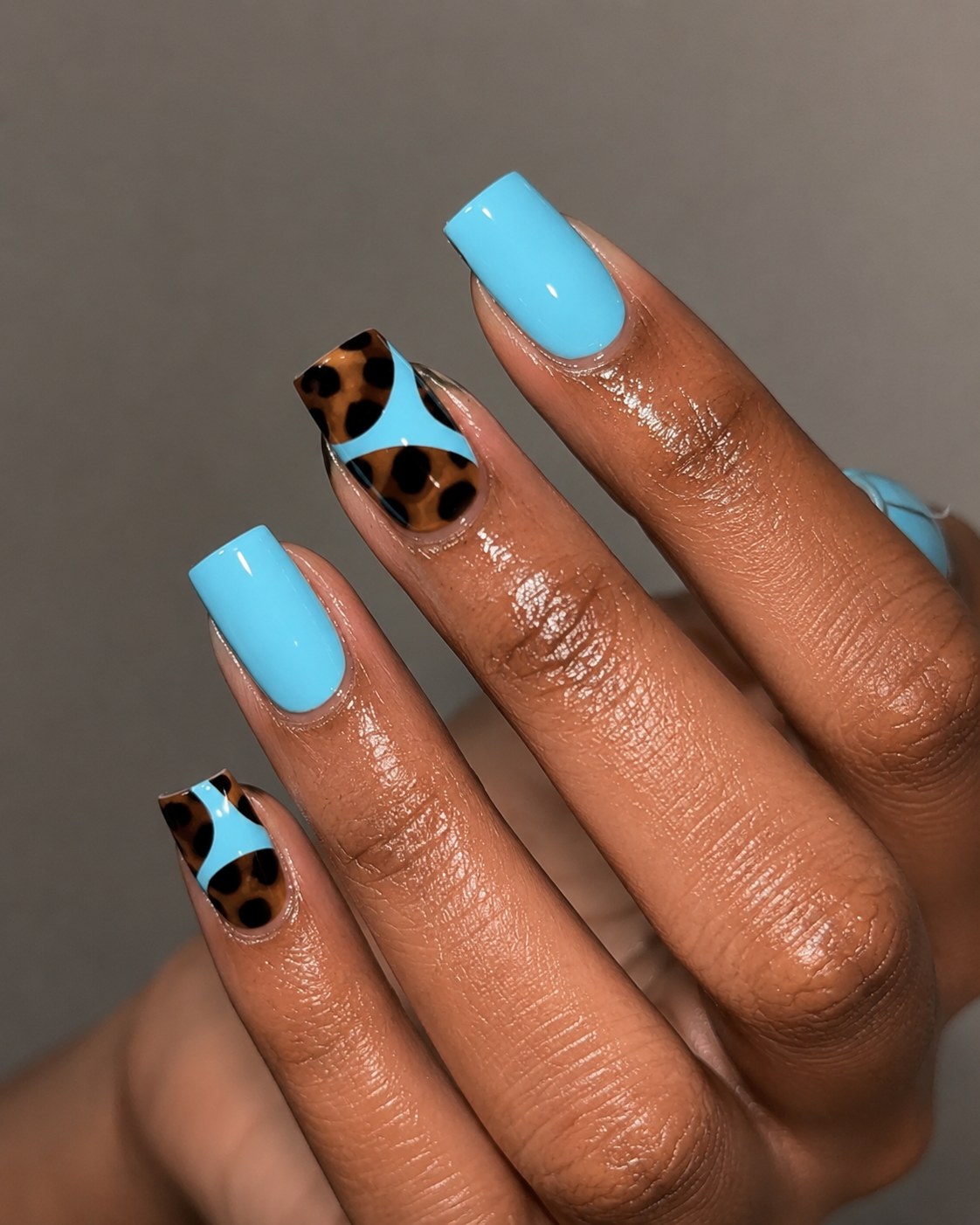 Square neon blue nails for dark skin with diagonal leopard print accent nails on two fingers
