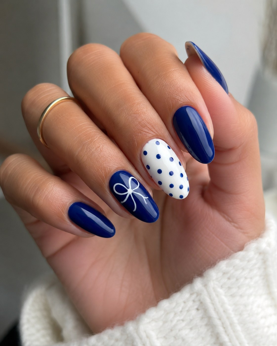 Navy blue nails with a polka dot bow accent nail, a bold nail color for dark skin