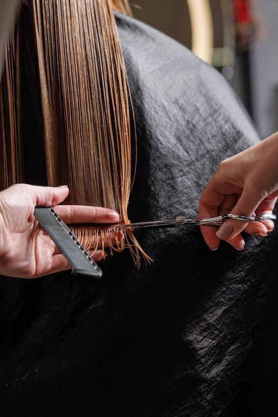 Hairdresser trimming long hair ends
