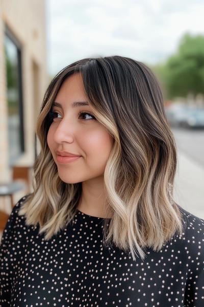 A young woman is showcasing a stylish shoulder-length bob with black hair accented by blonde highlights, creating a striking contrast and adding depth to her look.