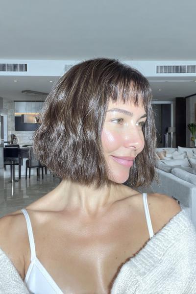 A woman with a softly tousled, chin-length bob hairstyle featuring short, blunt fringe.