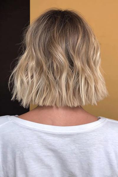 A short, wavy blonde bob haircut with softly textured ends, viewed from the back.