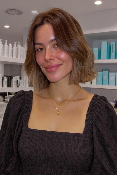 A woman with a chin-length bob hairstyle featuring subtle, face-framing layers and a middle part, without a visible fringe.
