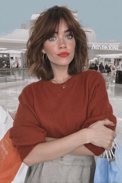 A woman with a tousled bob haircut featuring textured bangs, styled with soft waves for a relaxed yet chic look.