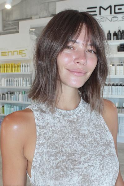 A woman with a short, textured bob haircut and soft, wispy fringe, styled in a tousled, natural look.