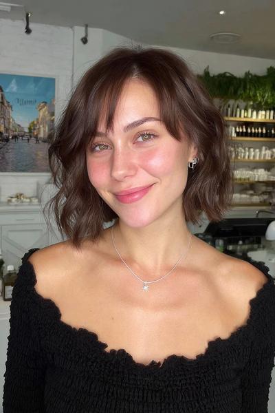 A woman with sleek, chin-length silver bob hair topped with a soft full fringe.
