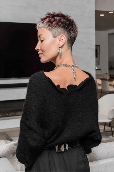 A woman with a short undercut pixie hairstyle, featuring closely cropped sides and back with slightly longer, textured hair on top.