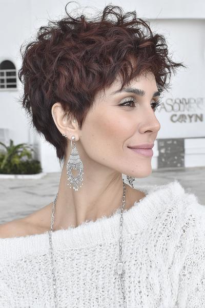 A woman with a stylish undercut pixie hairstyle featuring short, textured waves on top and closely cropped sides.