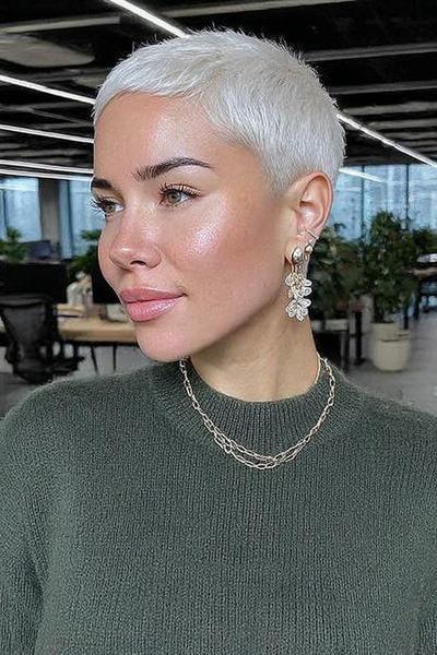 A woman with a platinum blonde undercut pixie hairstyle featuring very short, closely-cropped sides and back with slightly longer hair on top.
