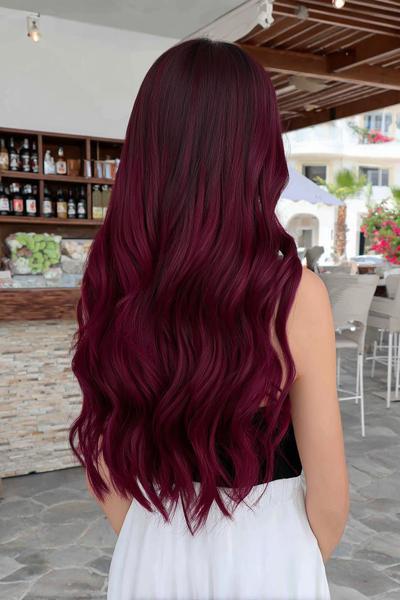 A woman with long, wavy dark red hair is shown from behind, with her hair cascading down her back.