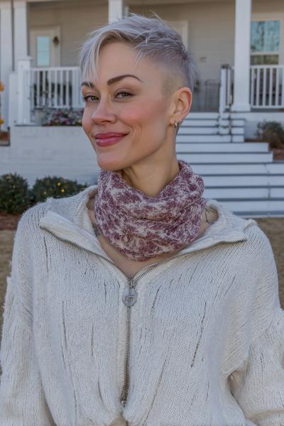 A woman with a short, undercut pixie hairstyle featuring longer, textured layers on top and closely shaved sides, with platinum blonde hair.