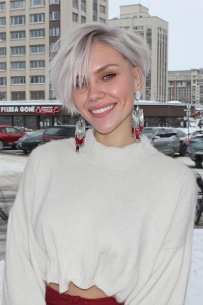 A woman with a short, platinum blonde undercut pixie hairstyle styled with long, textured layers on top and shorter sides.