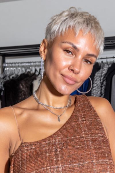 A woman with a platinum blonde undercut pixie hairstyle, featuring closely cropped sides and back with longer, textured layers on top.