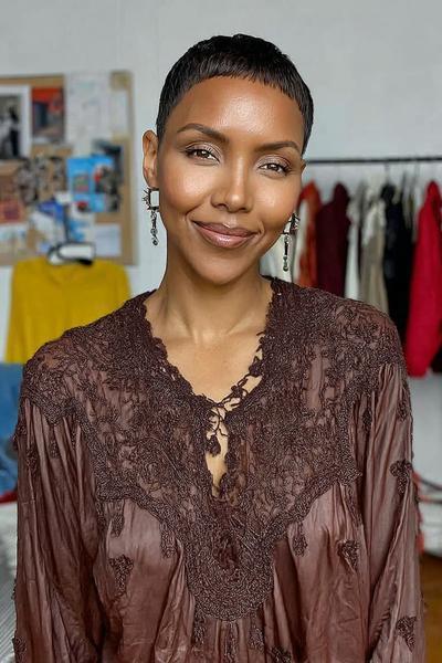 A woman with an undercut pixie hairstyle featuring very short, neatly cropped hair close to the scalp and slightly textured on top.