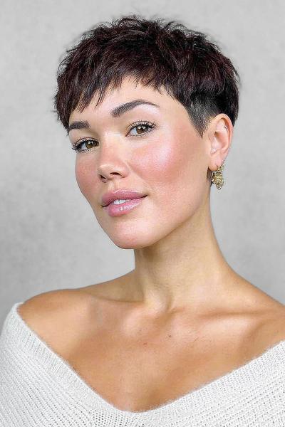 A woman with a textured, dark brown pixie cut featuring a short, tapered undercut on the sides and slightly longer, tousled layers on top.