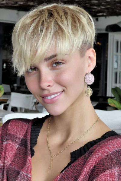 A young woman with a short, blonde undercut pixie hairstyle featuring textured, tousled layers on top and closely cropped sides.
