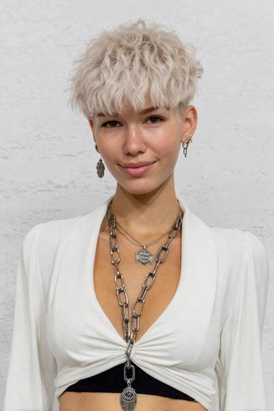 A young woman with platinum blonde hair wears an undercut pixie hairstyle featuring short, textured layers on top and closely cropped sides.