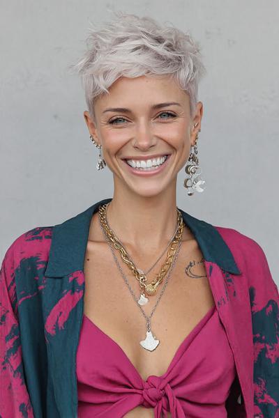 A woman with platinum blonde hair wears a textured, choppy pixie cut with an undercut, styled in a tousled and voluminous manner.