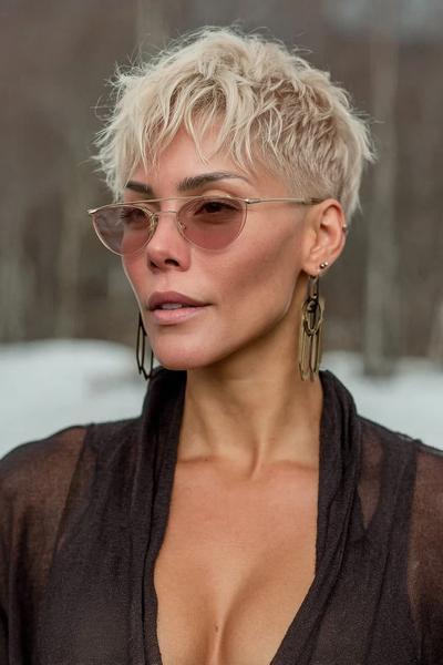 A woman with platinum blonde hair wears an undercut pixie hairstyle featuring short, textured layers on top and closely cropped sides.