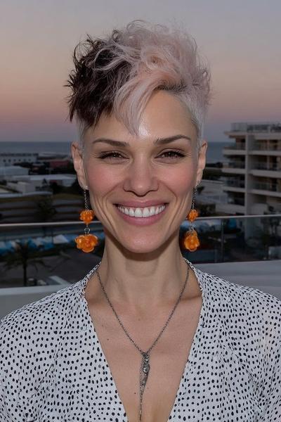 A woman with a stylish undercut pixie hairstyle featuring closely shaved sides and longer, tousled top layers in a mix of platinum blonde and dark brown shades.
