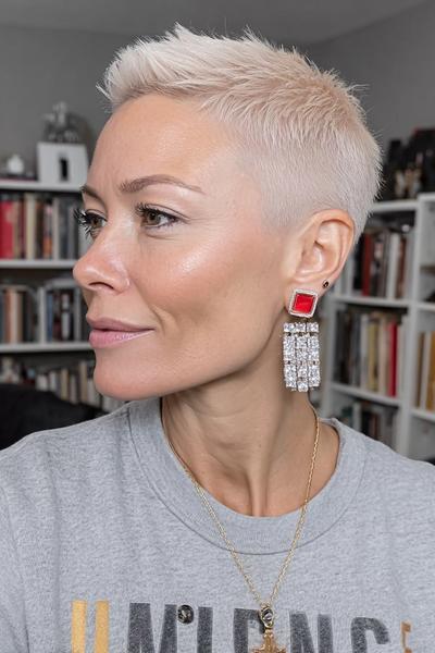 A woman with platinum blonde hair styled in a textured undercut pixie, featuring closely cropped sides and longer layers on top.