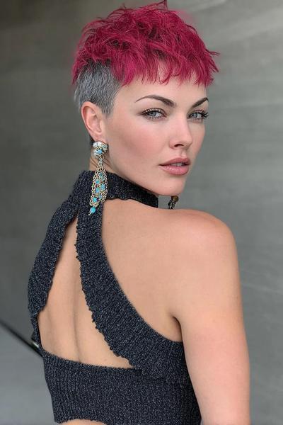A woman with a vibrant pink textured pixie cut featuring a short, closely-cropped grey undercut on the sides and back.