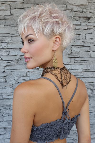 A woman with a textured platinum blonde pixie cut featuring choppy layers on top and a closely shaved undercut at the back.
