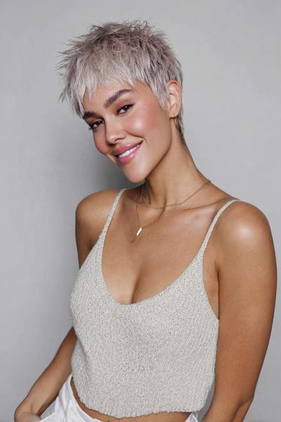 A woman with a short, textured undercut pixie hairstyle in a silvery-blonde shade, featuring longer layers on top and closely cropped sides.